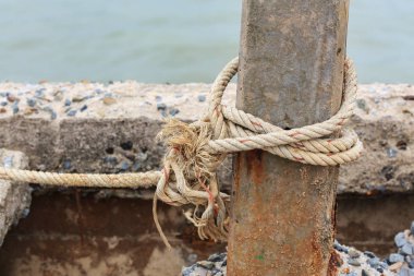 Eski beton direğin etrafında bağlı bir düğüm ile eski balıkçı teknesi halatı