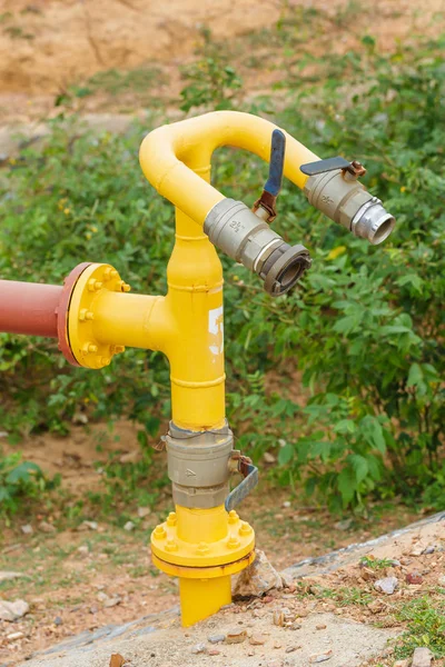 Vodní čerpadlo se žlutým ventilem a červená linka potrubí na pozadí přírody — Stock fotografie