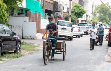 GHAZIABAD, UTTAR PRADESH / INDIA - Haziran 2020: Virüs ve Toz 'u önlemek için yüzünde tıbbi maske olan genç Hintli erkek işçi
