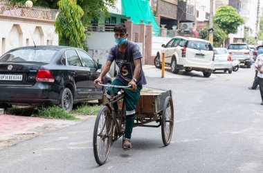 GHAZIABAD, UTTAR PRADESH / INDIA - Haziran 2020: Virüs ve Toz 'u önlemek için yüzünde tıbbi maske olan genç Hintli erkek işçi