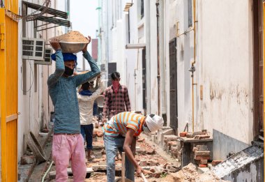 GHAZIABAD, UTTAR PRADESH / INDIA - Haziran 2020: Virüs ve Toz 'u önlemek için yüzünde tıbbi maske olan genç Hintli erkek işçi