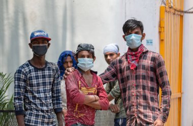 GHAZIABAD, UTTAR PRADESH / INDIA - Haziran 2020: Virüs ve Toz 'u önlemek için yüzünde tıbbi maske olan genç Hintli erkek işçi