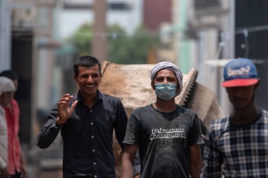 GHAZIABAD, UTTAR PRADESH / INDIA - Haziran 2020: Virüs ve Toz 'u önlemek için yüzünde tıbbi maske olan genç Hintli erkek işçi