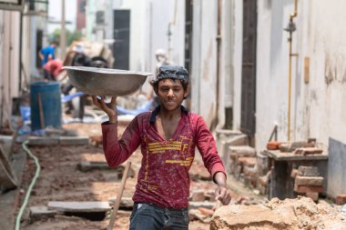 GHAZIABAD, UTTAR PRADESH / INDIA - Haziran 2020: Virüs ve Toz 'u önlemek için yüzünde tıbbi maske olan genç Hintli erkek işçi