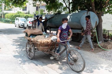 GHAZIABAD, UTTAR PRADESH / INDIA - Haziran 2020: Virüs ve Toz 'u önlemek için yüzünde tıbbi maske olan genç Hintli erkek işçi