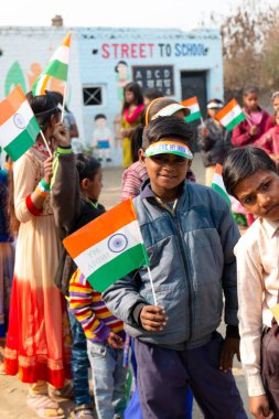 NOIDA, UTTAR PRADESH / INDIA - JANUARY 2020 : Young Indian students from Slum/Village area celebrating Indian Republic Day function at school with flags in hand clipart