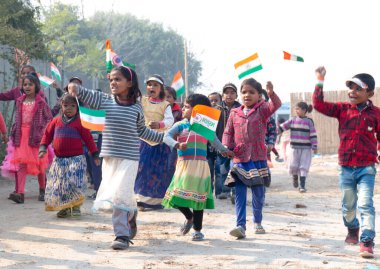 NOIDA, UTTAR PRADESH / INDIA - HAZİRAN 2020: Hindistan Cumhuriyeti Günü etkinliğini elinde bayraklarla kutlayan varoş / köy bölgesinden genç Hintli öğrenciler