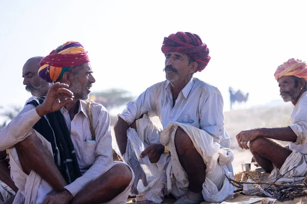 Puşkar, Rajasthan, Hindistan - 10 Kasım 2024: Geleneksel beyaz giysili rajasthani erkek portresi çöl panayırında renkli türbanlı deve fuarı sırasında develeri takas etmek için.