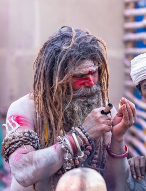 Varanasi, Uttar Pradesh, Hindistan - 21 Mart 2024: Masan Holi, Harishchandra ghat 'ta düzenlenen the Varanasi Holi festivali sırasında kimliği belirsiz bir erkek ağustos sadhu portresi.