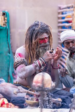 Varanasi, Uttar Pradesh, Hindistan - 21 Mart 2024: Masan Holi, Harishchandra ghat 'ta düzenlenen the Varanasi Holi festivali sırasında kimliği belirsiz bir erkek ağustos sadhu portresi.