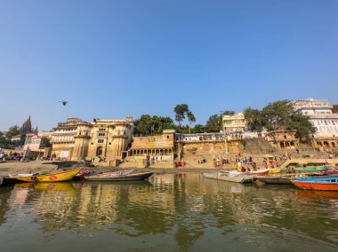 Varanasi, Uttar Pradesh, Hindistan - 17 Kasım 2022: Varanasi 'deki nehir çetelerinin yakınlarındaki ghatların mimari görüşü ve tapınakları. Ganga nehrinde yüzen tekneden binaların görüntüsü.