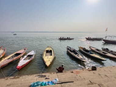 Varanasi, Uttar Pradesh, Hindistan - 18 Kasım 2022: Varanasi 'de kış sabahı nehir keneviri kıyısında yüzen ya da parkeden tahta botlar.