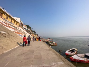 Varanasi, Uttar Pradesh, Hindistan - 18 Kasım 2022: Varanasi 'deki nehir çetelerinin yakınındaki ghat' larda bir grup insanla ahşap botlar.