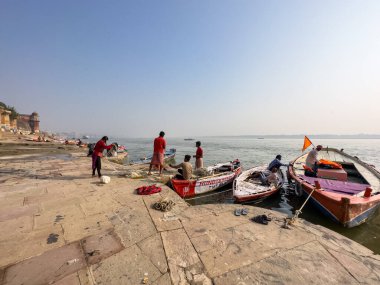 Varanasi, Uttar Pradesh, Hindistan - 18 Kasım 2022: Varanasi 'deki nehir çetelerinin yakınındaki ghat' larda bir grup insanla ahşap botlar.