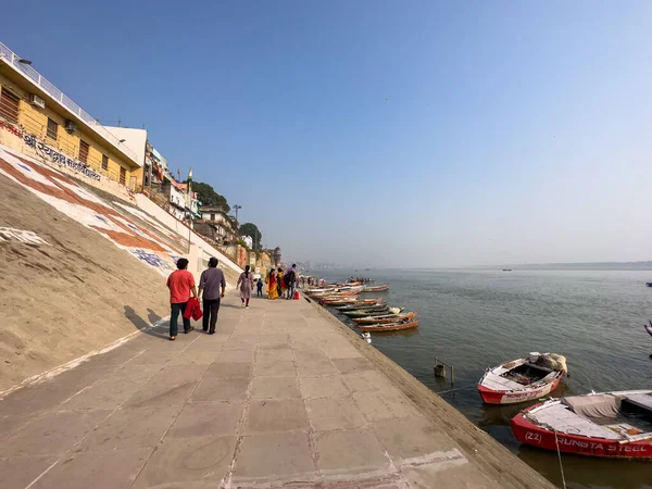 Varanasi, Uttar Pradesh, Hindistan - 18 Kasım 2022: Varanasi 'deki nehir çetelerinin yakınındaki ghat' larda bir grup insanla ahşap botlar.