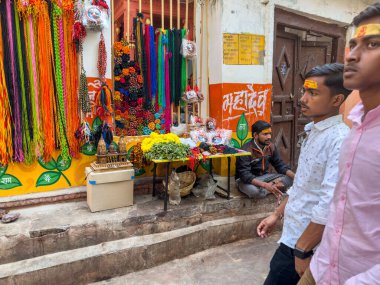 İki adam renkli süslemelerin ve çiçeklerin yanından geçiyor.