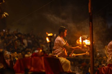Varanasi, Uttar Pradesh, Hindistan - 20 Mart 2024: Ganga aarti, genç erkek rahip dashashwamedh ghat geleneksel elbise ve hindu ritüelleri ile kutsal nehir kenevir akşam aarti performans.