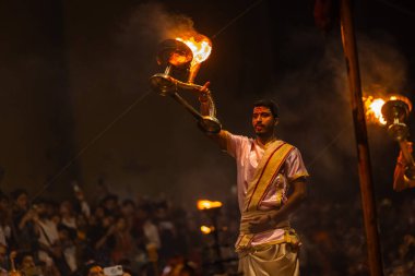 Varanasi, Uttar Pradesh, Hindistan - 20 Mart 2024: Ganga aarti, genç erkek rahip dashashwamedh ghat geleneksel elbise ve hindu ritüelleri ile kutsal nehir kenevir akşam aarti performans.