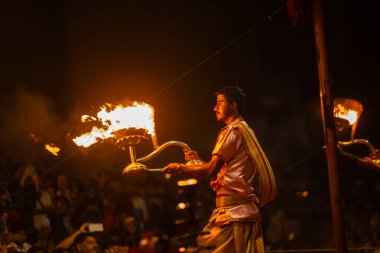 Varanasi, Uttar Pradesh, Hindistan - 20 Mart 2024: Ganga aarti, genç erkek rahip dashashwamedh ghat geleneksel elbise ve hindu ritüelleri ile kutsal nehir kenevir akşam aarti performans.
