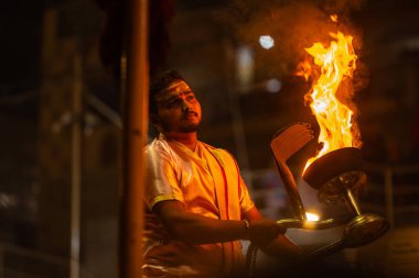 Varanasi, Uttar Pradesh, Hindistan - 20 Mart 2024: Ganga aarti, genç erkek rahip dashashwamedh ghat geleneksel elbise ve hindu ritüelleri ile kutsal nehir kenevir akşam aarti performans.