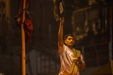 Varanasi, Uttar Pradesh, Hindistan - 20 Mart 2024: Ganga aarti, genç erkek rahip dashashwamedh ghat geleneksel elbise ve hindu ritüelleri ile kutsal nehir kenevir akşam aarti performans.