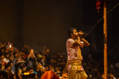 Varanasi, Uttar Pradesh, Hindistan - 20 Mart 2024: Ganga aarti, genç erkek rahip dashashwamedh ghat geleneksel elbise ve hindu ritüelleri ile kutsal nehir kenevir akşam aarti performans.