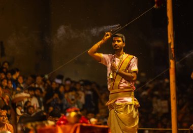 Varanasi, Uttar Pradesh, Hindistan - 20 Mart 2024: Ganga aarti, genç erkek rahip dashashwamedh ghat geleneksel elbise ve hindu ritüelleri ile kutsal nehir kenevir akşam aarti performans.