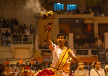 Varanasi, Uttar Pradesh, Hindistan - 20 Mart 2024: Ganga aarti, genç erkek rahip dashashwamedh ghat geleneksel elbise ve hindu ritüelleri ile kutsal nehir kenevir akşam aarti performans.