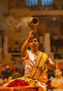 Varanasi, Uttar Pradesh, Hindistan - 20 Mart 2024: Ganga aarti, genç erkek rahip dashashwamedh ghat geleneksel elbise ve hindu ritüelleri ile kutsal nehir kenevir akşam aarti performans.