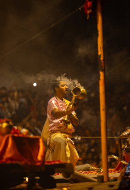 Varanasi, Uttar Pradesh, Hindistan - 20 Mart 2024: Ganga aarti, genç erkek rahip dashashwamedh ghat geleneksel elbise ve hindu ritüelleri ile kutsal nehir kenevir akşam aarti performans.