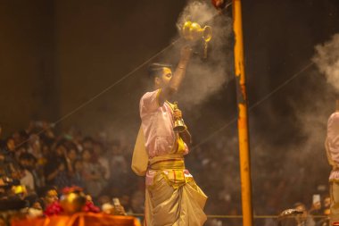 Varanasi, Uttar Pradesh, Hindistan - 20 Mart 2024: Ganga aarti, genç erkek rahip dashashwamedh ghat geleneksel elbise ve hindu ritüelleri ile kutsal nehir kenevir akşam aarti performans.