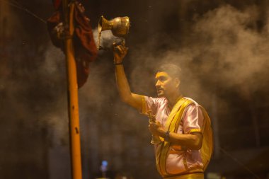 Varanasi, Uttar Pradesh, Hindistan - 20 Mart 2024: Ganga aarti, genç erkek rahip dashashwamedh ghat geleneksel elbise ve hindu ritüelleri ile kutsal nehir kenevir akşam aarti performans.