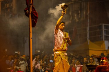 Varanasi, Uttar Pradesh, Hindistan - 20 Mart 2024: Ganga aarti, genç erkek rahip dashashwamedh ghat geleneksel elbise ve hindu ritüelleri ile kutsal nehir kenevir akşam aarti performans.
