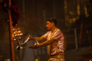 Varanasi, Uttar Pradesh, Hindistan - 20 Mart 2024: Ganga aarti, genç erkek rahip dashashwamedh ghat geleneksel elbise ve hindu ritüelleri ile kutsal nehir kenevir akşam aarti performans.