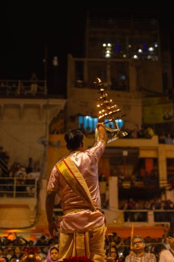 Varanasi, Uttar Pradesh, Hindistan - 20 Mart 2024: Ganga aarti, genç erkek rahip dashashwamedh ghat geleneksel elbise ve hindu ritüelleri ile kutsal nehir kenevir akşam aarti performans.