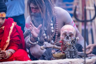 Varanasi, Uttar Pradesh, India - March 21, 2024: Masan Holi, Portrait of an unidentified aghori sadhu smoking and performing rituals during masan holi festival in varanasi at harishchandra ghat.