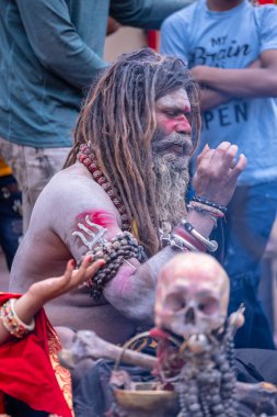 Varanasi, Uttar Pradesh, India - March 21, 2024: Masan Holi, Portrait of an unidentified aghori sadhu smoking and performing rituals during masan holi festival in varanasi at harishchandra ghat.