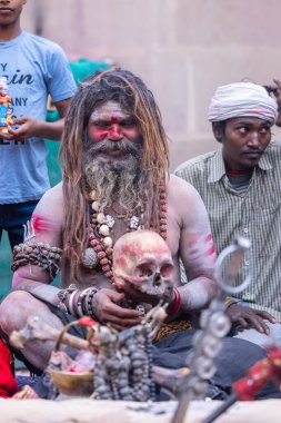 Varanasi, Uttar Pradesh, India - March 21, 2024: Masan Holi, Portrait of an unidentified aghori sadhu smoking and performing rituals during masan holi festival in varanasi at harishchandra ghat.