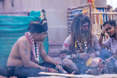 Varanasi, Uttar Pradesh, India - March 21, 2024: Masan Holi, Portrait of an unidentified aghori sadhu smoking and performing rituals during masan holi festival in varanasi at harishchandra ghat.