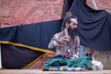 Varanasi, Uttar Pradesh, India - March 21, 2024: Masan Holi, Portrait of an unidentified aghori sadhu smoking and performing rituals during masan holi festival in varanasi at harishchandra ghat.