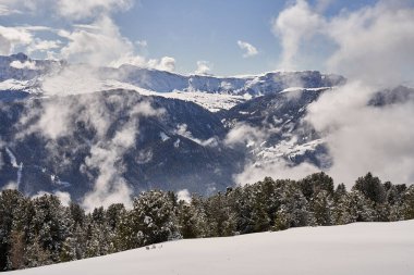 Güneşli bir kış gününde bulutların içindeki dağların manzarası
