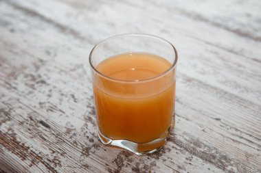 Tahta masada bir bardak taze sıkılmış portakal suyu.