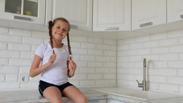 Niña en la cocina sonríe y ríe . — Vídeo de stock