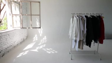 Beyaz duvarın yanında şık kıyafetler olan gardırop rafı. Metin için boşluk