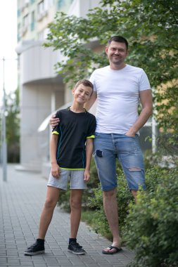 Baba ve oğul yazın sokakta beraber yürüyorlar.