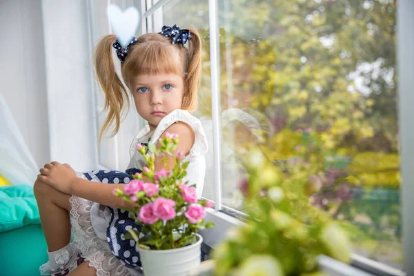 A little sweet girl by the window. happy childhood