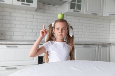 Mutfakta kafasında elma olan küçük bir kız. yeni fikir.