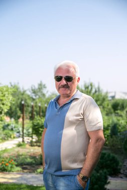 Yazın güneş gözlüklü, kır saçlı adam.