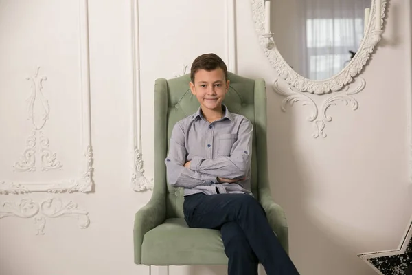 男孩坐在一张漂亮的椅子上 摄影工作室 — 图库照片