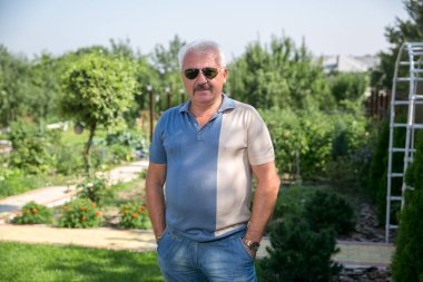 Yazın güneş gözlüklü, kır saçlı adam.